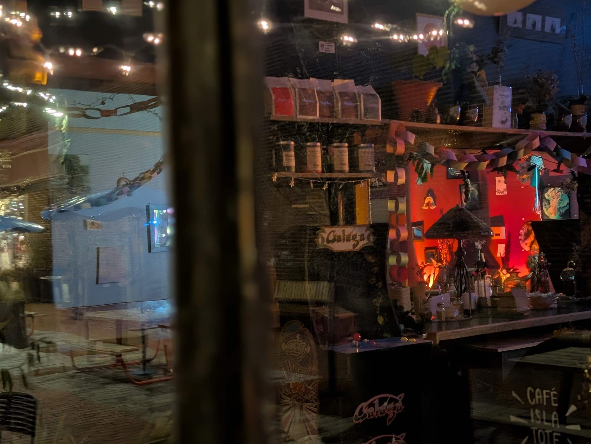 looking through the window into a coffee shop, with the reflection of a table and chairs just outside.