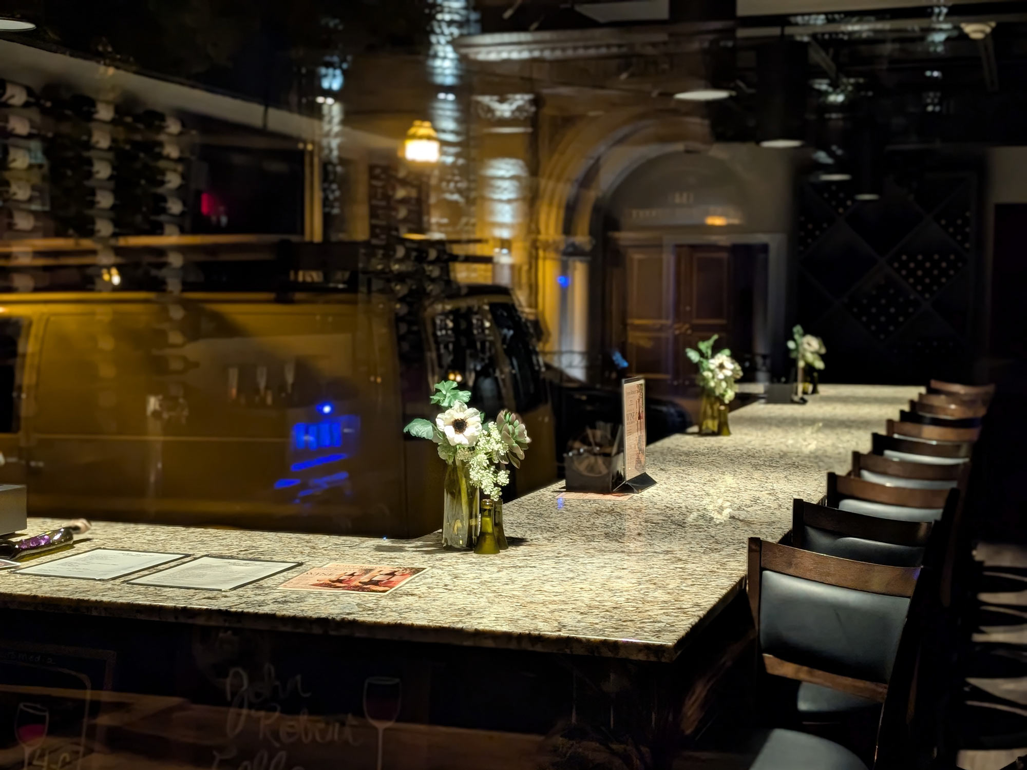 Countertop in a darkened restaurant, lit from above, seen through an image of the street outside reflected in the window