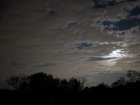 A full moon illuminating the clouds surrounding it