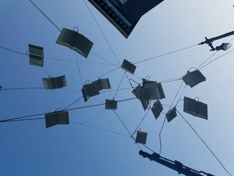 Open books, suspended with thin cables crisscrossing above