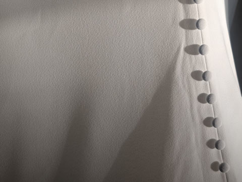 A column of small white buttons climbing up the back of a wedding gown