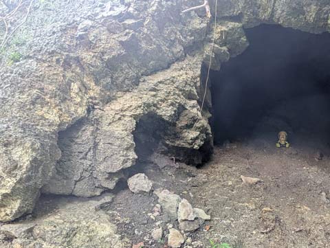 a ceramic head of a man sitting just with the mouth of a small cave