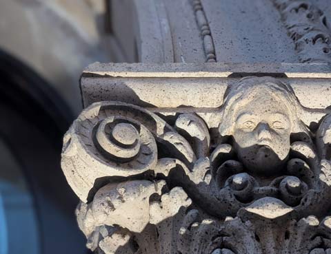 A small gargoyle head that has the appearance of a child looking morosely downward