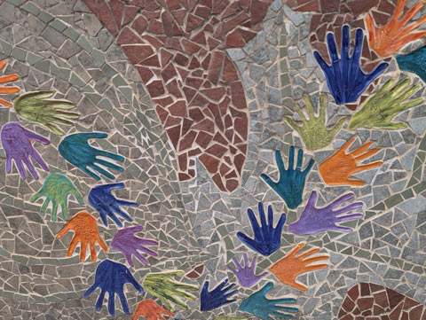 Multi-colored hand print tiles that are part of a wall mosaic