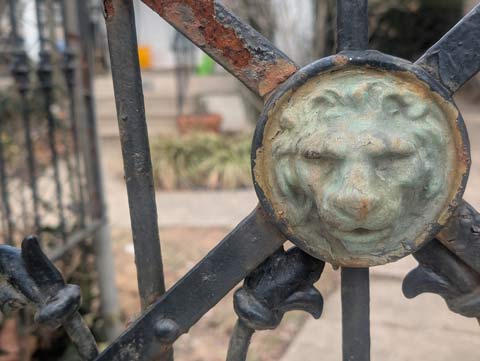 Lions head medallion affixed to a wrought iron gate