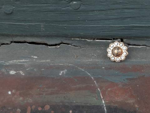 A golden earring, made up of a large dark gold circle surrounded by smaller circles of fake diamonds