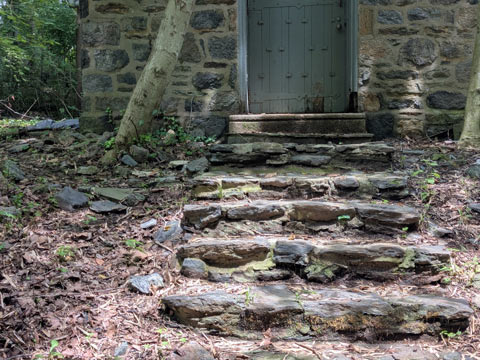 Steps made of field stones leading up to an old weathered door.