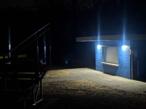 Baseball park concession stand, closed for the season, with security lights shining, looking like the face of an old man wearing a dissaproving look on his face