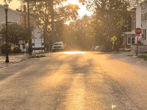 Sunlight reflecting brightly on the surface of a street during a sun shower